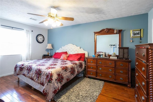 bedroom with ceiling fan, dark hardwood / wood-style floors, and a textured ceiling