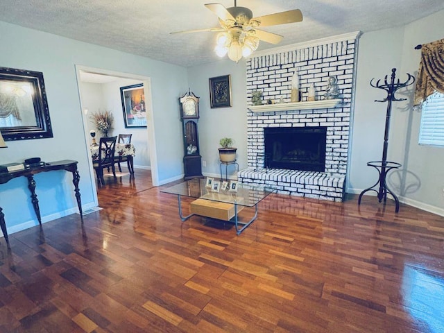 living room featuring ceiling fan, dark hardwood / wood-style floors, a brick fireplace, and a textured ceiling