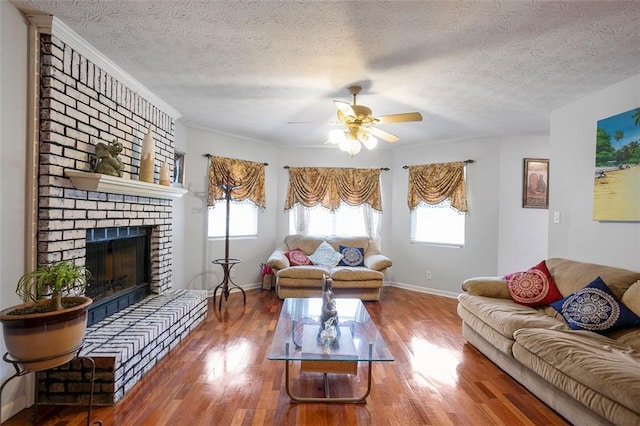 living room with a brick fireplace, hardwood / wood-style floors, a textured ceiling, and ceiling fan