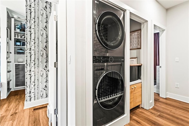 clothes washing area with stacked washer and dryer and light hardwood / wood-style flooring