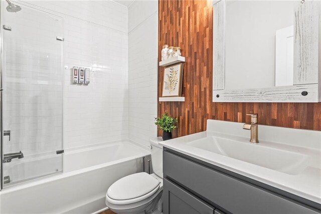 full bathroom with vanity, wood walls, toilet, and tub / shower combination