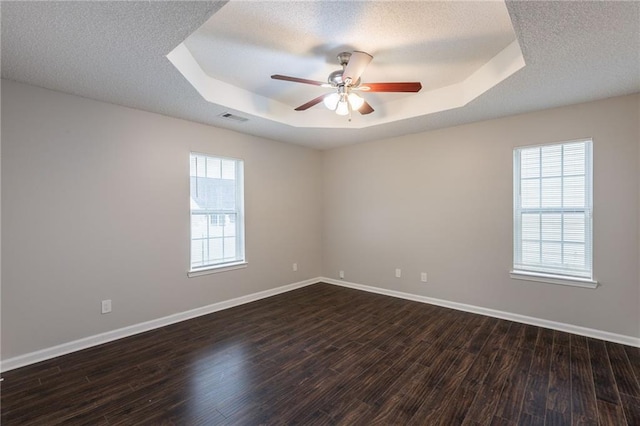 empty room with visible vents, a raised ceiling, ceiling fan, and baseboards