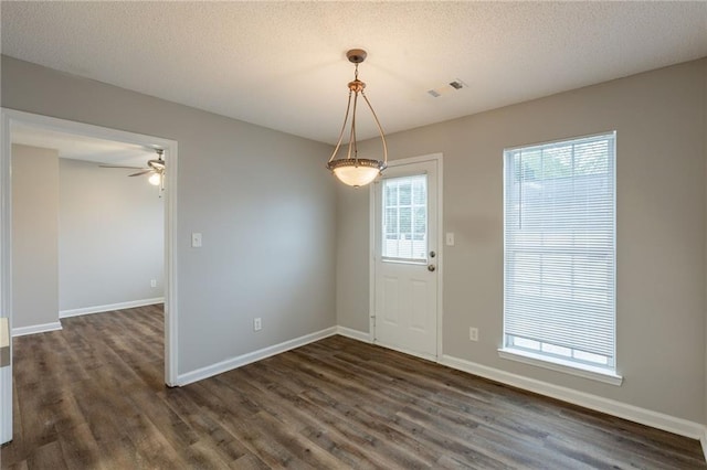 unfurnished dining area featuring baseboards, ceiling fan, and dark wood-type flooring