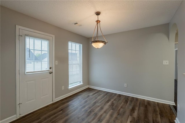interior space featuring baseboards, arched walkways, dark wood-style floors, and visible vents