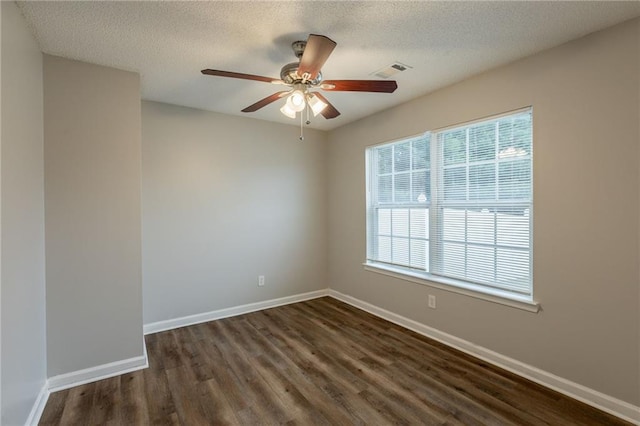 unfurnished room featuring visible vents, dark wood-style flooring, baseboards, ceiling fan, and a textured ceiling