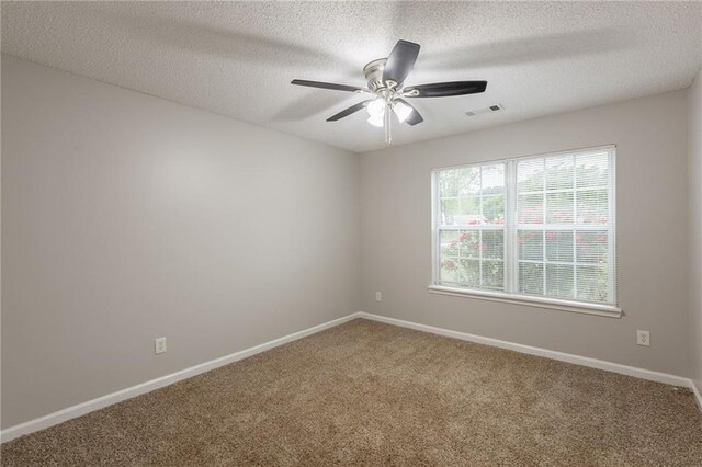 carpeted empty room with a textured ceiling, baseboards, visible vents, and a ceiling fan