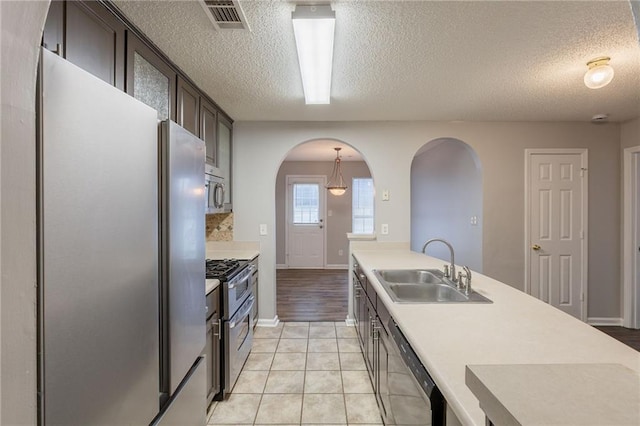 kitchen with visible vents, a textured ceiling, arched walkways, a sink, and appliances with stainless steel finishes