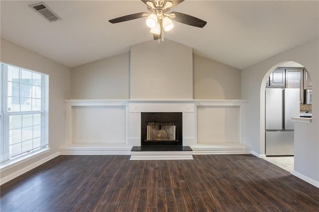 unfurnished living room with ceiling fan, visible vents, dark wood finished floors, baseboards, and lofted ceiling