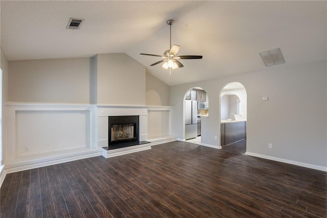 unfurnished living room featuring dark wood-style flooring, ceiling fan, visible vents, and a fireplace with raised hearth
