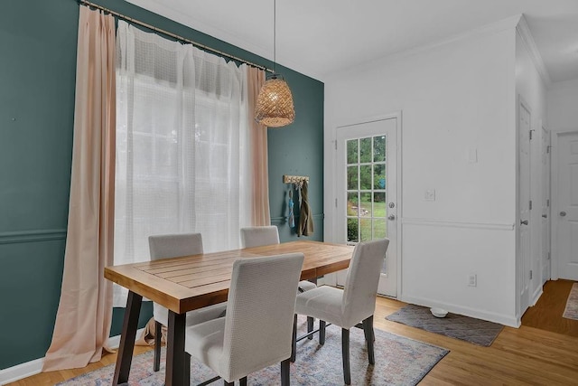 dining space with crown molding and light wood finished floors