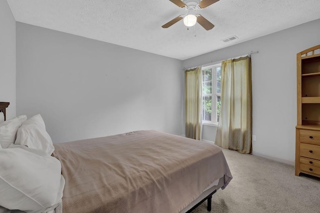 bedroom featuring light carpet, a textured ceiling, baseboards, and ceiling fan
