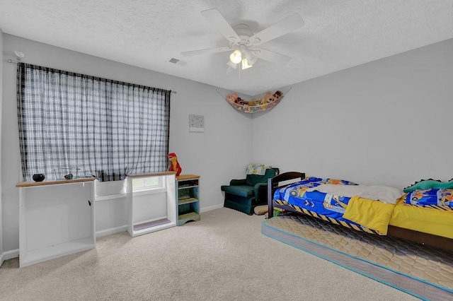 carpeted bedroom with a textured ceiling, ceiling fan, and baseboards