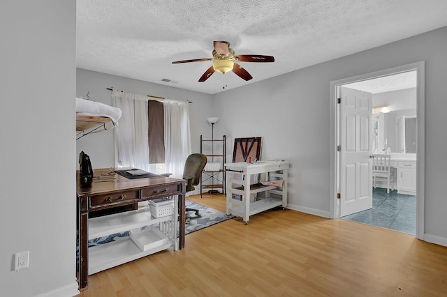 office space featuring ceiling fan, wood finished floors, baseboards, and a textured ceiling