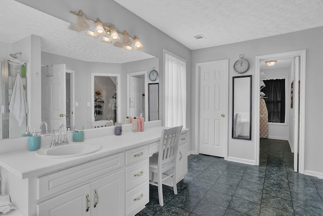 bathroom featuring vanity, a textured ceiling, and baseboards