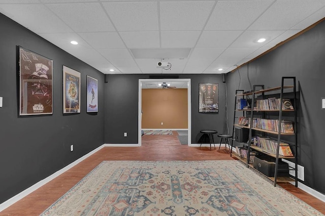 sitting room featuring wood finished floors, baseboards, a drop ceiling, recessed lighting, and a ceiling fan