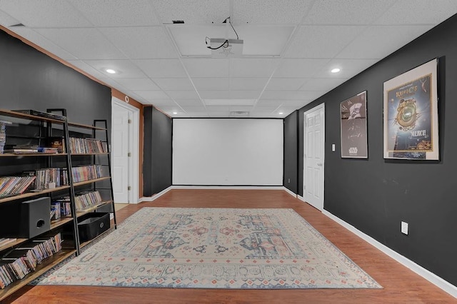 cinema room with a drop ceiling, wood finished floors, baseboards, and recessed lighting
