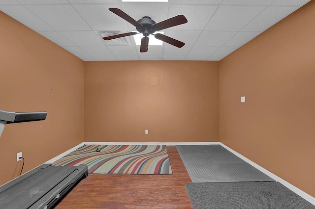 workout room with a paneled ceiling, a ceiling fan, baseboards, and wood finished floors