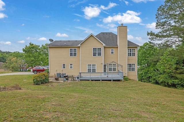back of property with a chimney, a yard, a wooden deck, and a patio