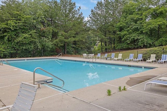 community pool featuring fence, a patio, and view of scattered trees