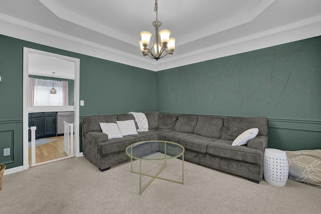 living room with a chandelier, a tray ceiling, carpet, and crown molding