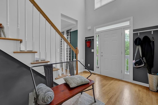 entrance foyer with stairs, wood finished floors, a high ceiling, and baseboards
