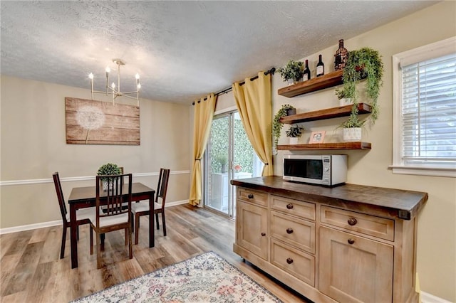 6700 Roswell Rd Unit 22B, Atlanta, GA 30328 - dining area featuring a textured ceiling, light wood finished floors, a chandelier, and baseboards