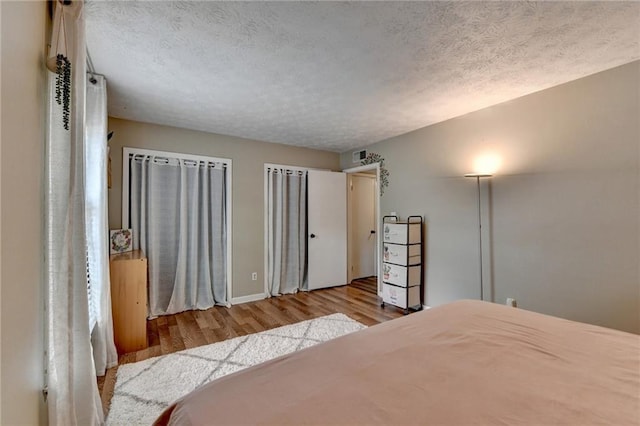 6700 Roswell Rd Unit 22B, Atlanta, GA 30328 - bedroom with wood finished floors, a textured ceiling, baseboards, and multiple closets