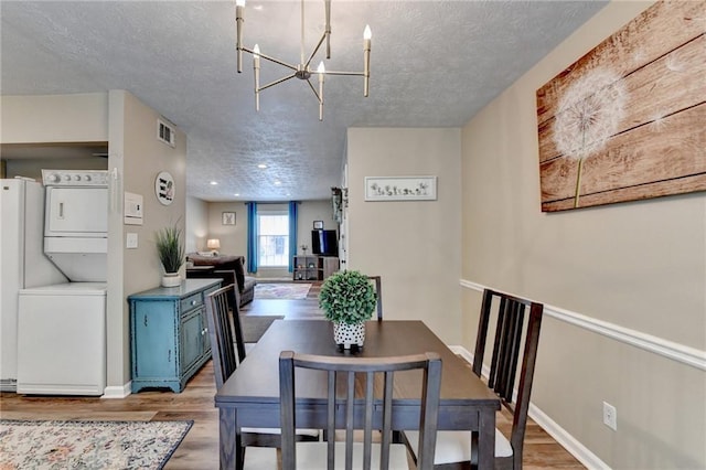 6700 Roswell Rd Unit 22B, Atlanta, GA 30328 - dining area with stacked washing machine and dryer, a textured ceiling, wood finished floors, a chandelier, and baseboards