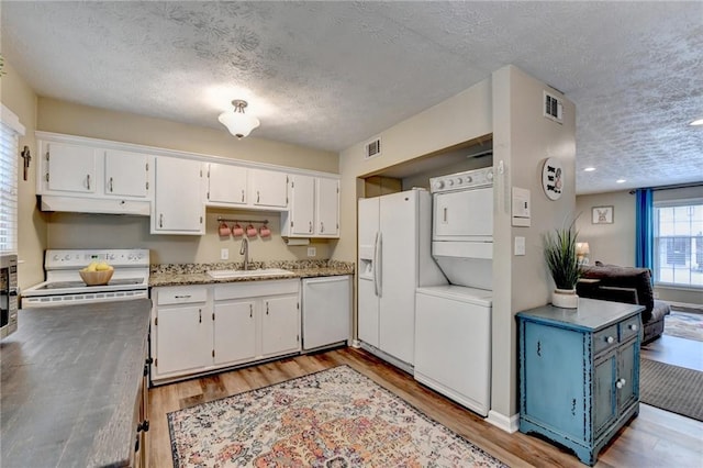 6700 Roswell Rd Unit 22B, Atlanta, GA 30328 - kitchen featuring a sink, stacked washer / dryer, white appliances, a textured ceiling, and under cabinet range hood