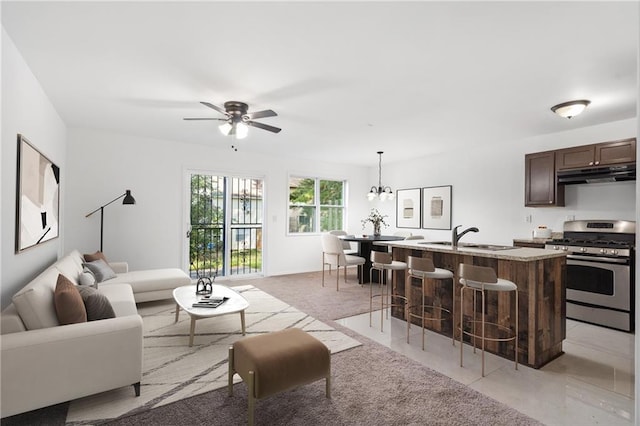 living area with ceiling fan with notable chandelier