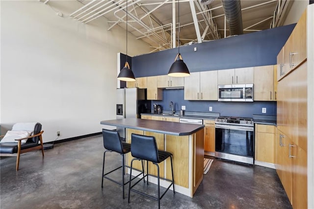 kitchen featuring sink, a towering ceiling, a kitchen island, pendant lighting, and appliances with stainless steel finishes