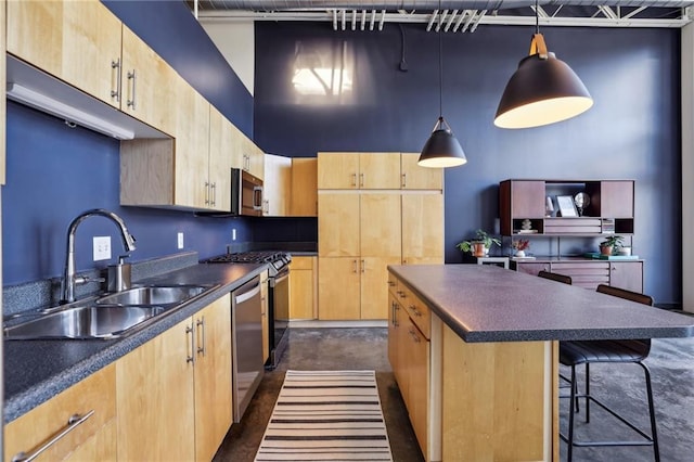 kitchen featuring sink, light brown cabinetry, hanging light fixtures, a kitchen island, and appliances with stainless steel finishes