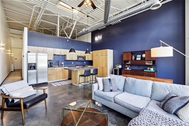 living room featuring a towering ceiling, sink, and ceiling fan