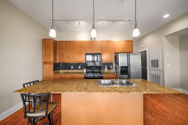 kitchen featuring black appliances, a breakfast bar, pendant lighting, sink, and backsplash