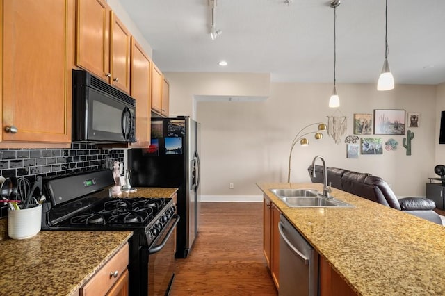 kitchen with light stone countertops, pendant lighting, black appliances, backsplash, and sink