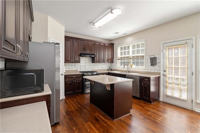 kitchen featuring appliances with stainless steel finishes, under cabinet range hood, dark brown cabinetry, light countertops, and backsplash