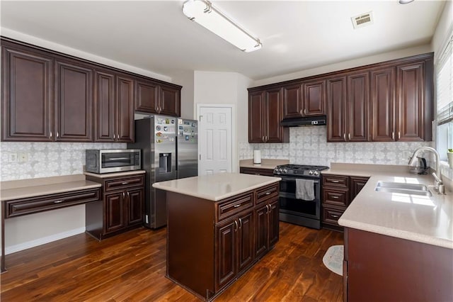 kitchen featuring appliances with stainless steel finishes, a sink, under cabinet range hood, a kitchen island, and dark brown cabinets