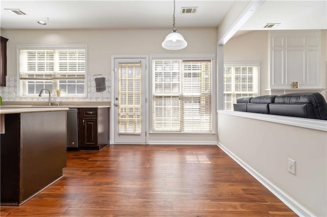 kitchen with light countertops, dark brown cabinetry, healthy amount of natural light, and dark wood finished floors