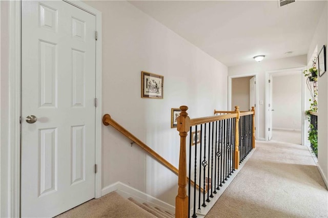 hallway with an upstairs landing, carpet flooring, and baseboards