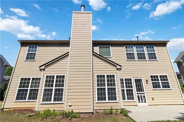 rear view of house with a chimney and a patio