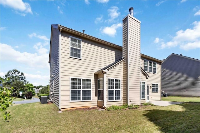 rear view of property featuring a chimney, central AC, and a lawn