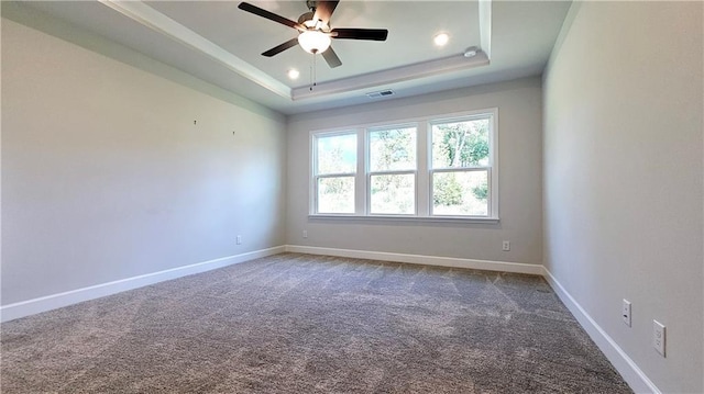 empty room featuring ceiling fan, a raised ceiling, and carpet floors