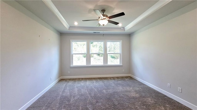 carpeted spare room featuring a raised ceiling, ornamental molding, and ceiling fan