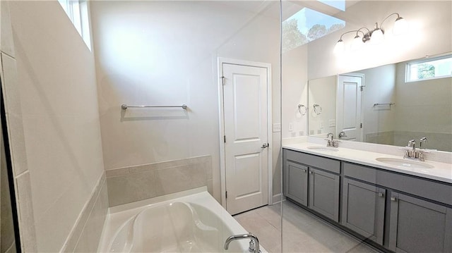 bathroom with tile patterned flooring, vanity, and a bath