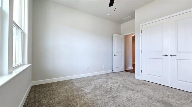 unfurnished bedroom with light carpet, ceiling fan, and a closet