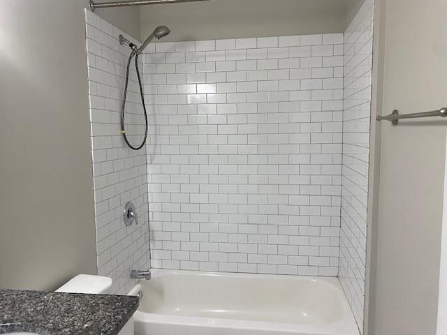 full bathroom with vanity, tiled shower / bath, and toilet