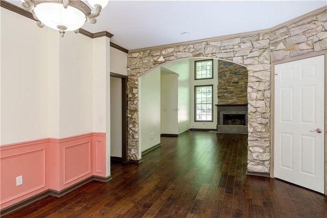 540 Branch Dr, Pendergrass, GA 30567 - unfurnished living room featuring arched walkways, wood-type flooring, crown molding, a stone fireplace, and wainscoting