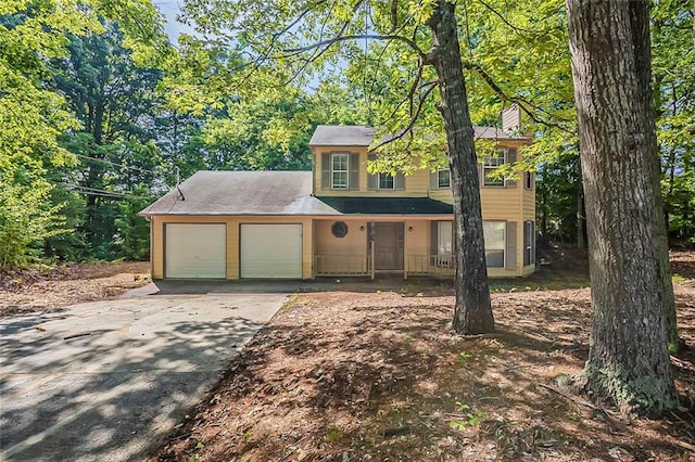 colonial inspired home featuring a chimney, an attached garage, and driveway
