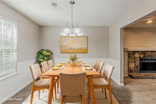 dining space with carpet, a chandelier, baseboards, and a fireplace