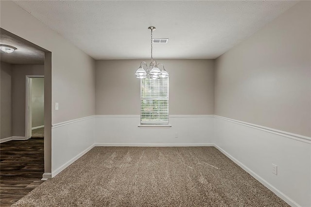 carpeted spare room with a chandelier, baseboards, and a textured ceiling